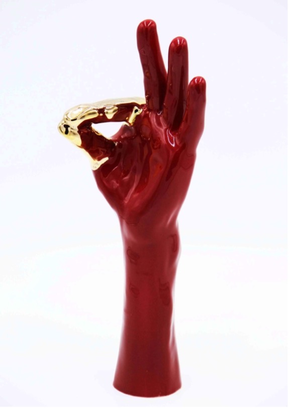Red ceramic hand in an ASL flat 9/flat F handshape. The index finger and the thumb are painted gold.